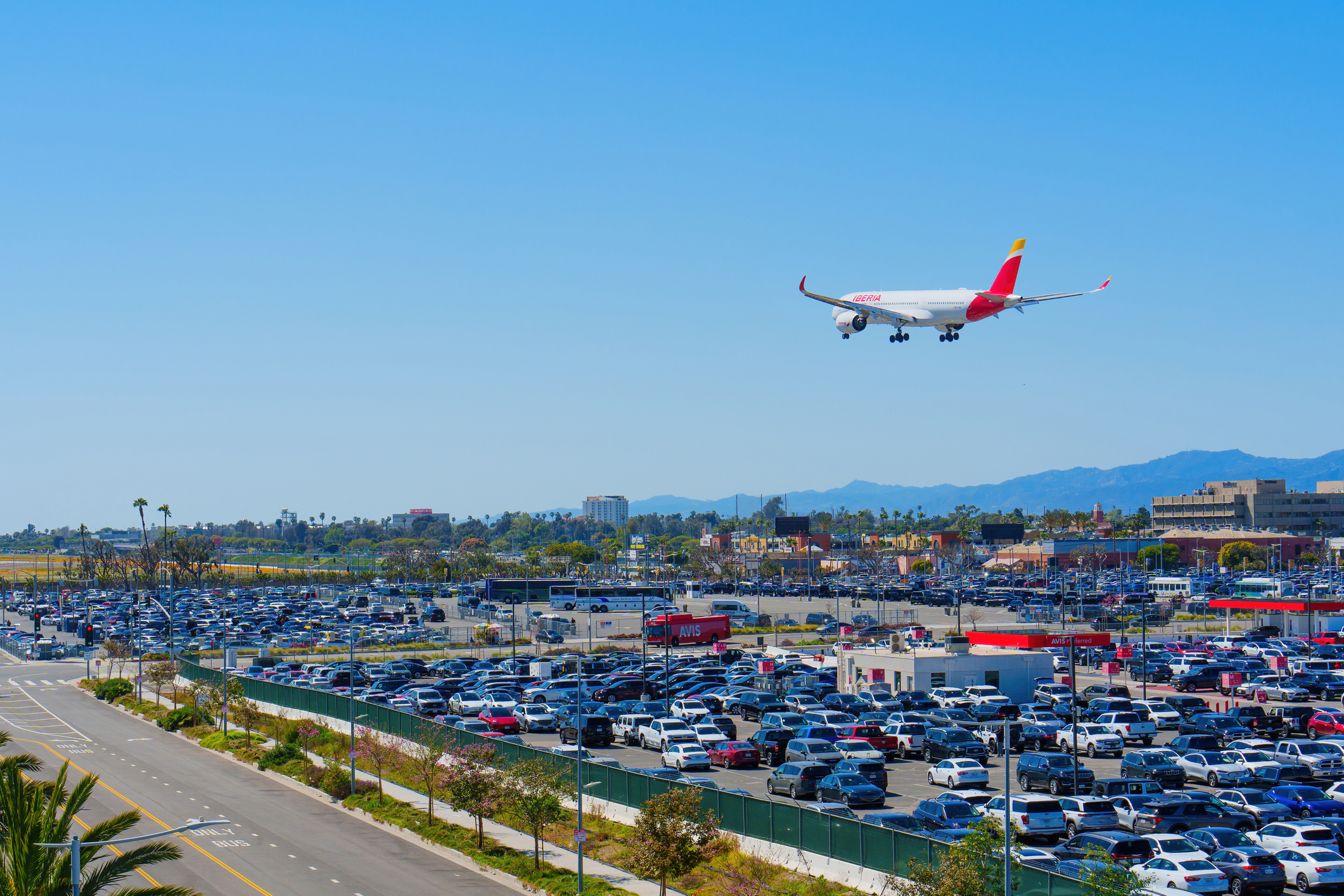 Los Angeles, California - April 9, 2024: Iberia Airlines plane soaring over the LAX Parking lot, set against the backdrop of a clear blue sky on a sunny day.